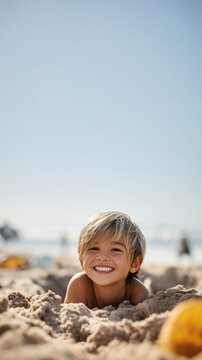 Young boy smiling while buried in sand at beach on sunny shoreline