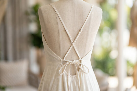 Light backless summer linen dress on mannequin with crisscross straps and bow tie for fashion display and e commerce product background