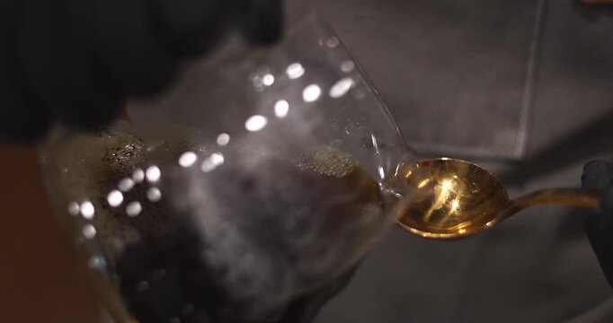 Barista pours fresh brewed coffee from a glass server for tasting with a cupping spoon