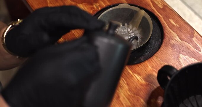 Barista places rinsed paper filter securely into pour over dripper before adding coffee grounds, wetting to set filter in place and prep for even optimal distribution of coffee