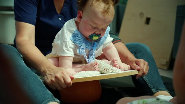 Baby learning to balance on an exercise board with the help of a physiotherapist, supporting motor skill development