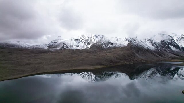 Drone view of beautiful snow covered mountains and peaceful lake, Ama Drime Snow Mountain and Dingjie Zongcuo Lake in Dingjie, Shigatse, Tibet, China. Travel concept 4k real time footage aerial view.