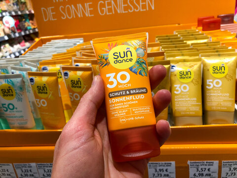 Varna, Bulgaria - May 11, 2026: DM SPF sun skin, hair protection creams and balms. Sunburn protection. Tan solar fluid. Hand holding Sun Dance sunscreen in store with various products in background