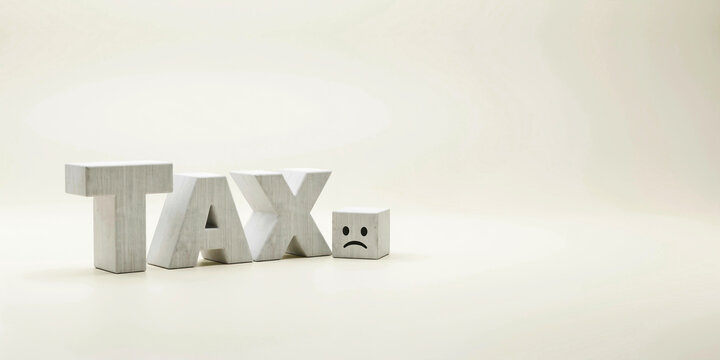 Tax burden concept with sad face symbol on white letters for financial stress, taxation and income deduction