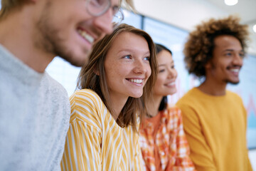 Obraz premium Young adults smile brightly in a casual group setting. Their expressions show warmth and joyful engagement. The scene suggests collaborative learning or creative teamwork