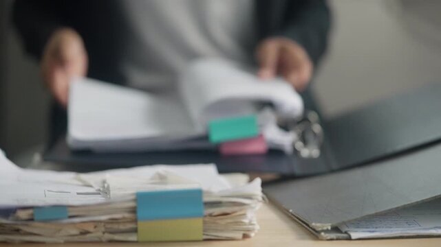 Office Employee Reviewing Large Stack of Business Files and Administrative Documents