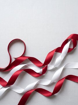 Elegant red and white satin ribbon curl on white background. Luxury gift wrapping bow decoration for packaging and crafts.