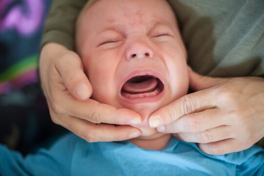 Little one's first tearful symphony as a tiny tooth begins its challenging emergence, bringing a wave of discomfort and a parent's gentle care