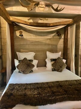 Lit &agrave; baldaquin en bois dans une chambre au style rustique et chaleureux
