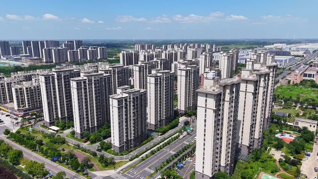 Aerial panoramic view of modern high-rise residential community with green landscape under blue sky