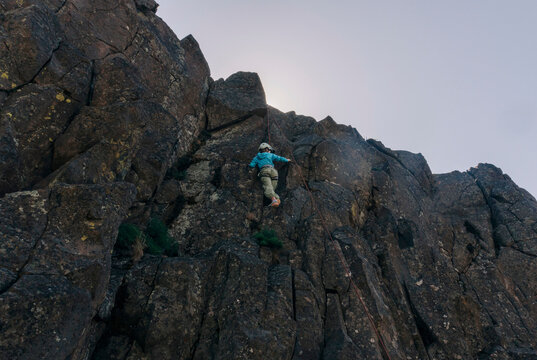 Climber ascends a rugged rock face at dawn