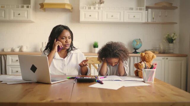 Emotional black woman screaming when calling phone, child girl covering ears. Angry boss or housewife arguing with someone, modern work-from-home mother, scared african american preschooler girl