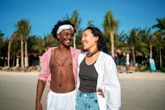 Happy young couple embracing and laughing on a tropical beach during summer vacation