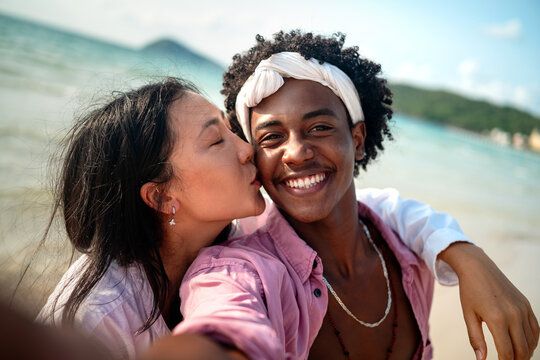 Romantic interracial couple enjoying a tropical honeymoon on a beach, embracing love and happiness