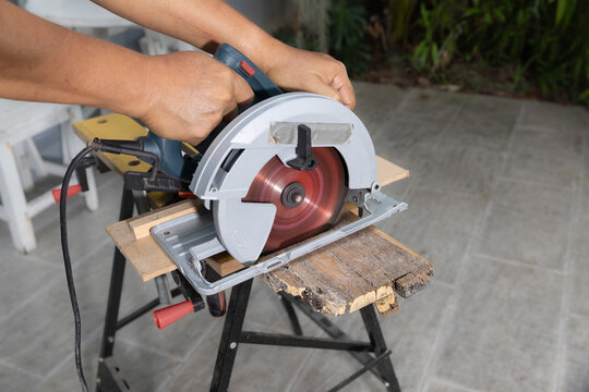 Circular saw cross cutting out rotten wood plank on sawhorses.