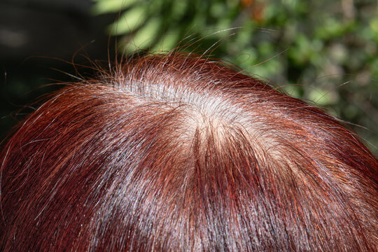 Senior aged asian woman concern about gray hair in menopause.