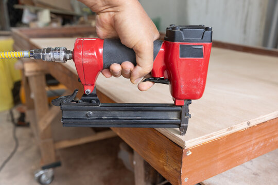 Nail gun is nailing on plywood in wood workshop.
