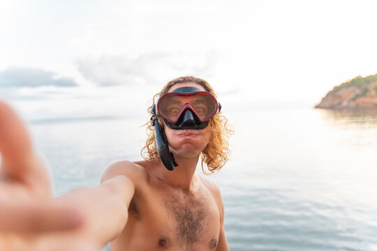 Young man with snorkel making a face on the beach