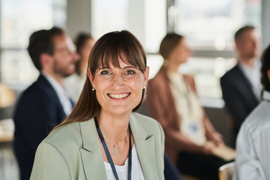 Smiling female entrepreneur with colleagues at educational event