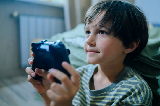 Child playing video game with controller at home