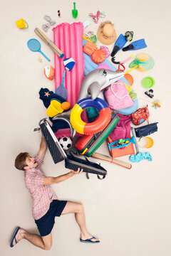 Man struggling with overflowing holiday luggage in studio setting