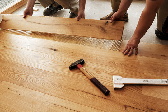 Two men laying finished parquet flooring, close-up