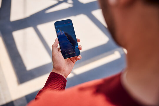 Checking stock market loss on smartphone application outdoors