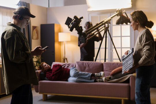 Film crew works on set with an actress lying on a sofa