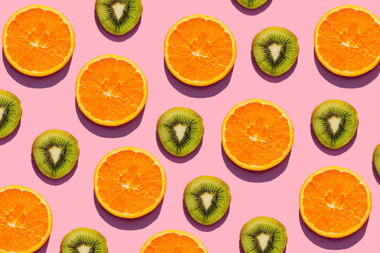 Pattern of orange and kiwi fruit slices against pink background