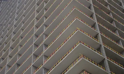 Modern concrete skyscraper under construction with yellow safety barriers and copy space © Aliaksei