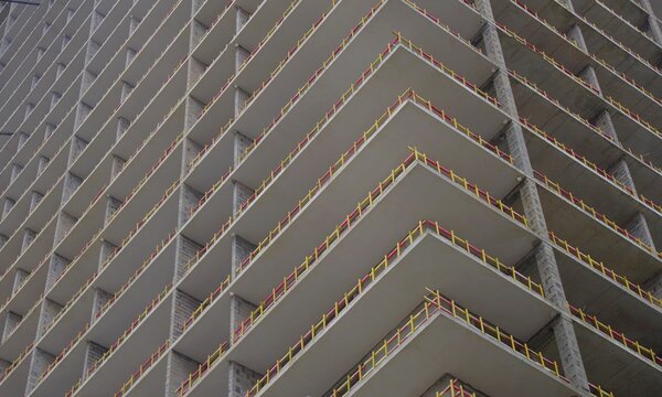 Modern concrete skyscraper under construction with yellow safety barriers and copy space