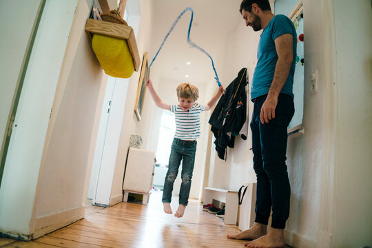 Playful boy jumping over skipping rope at home