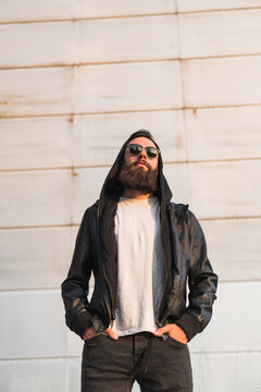 Cool bearded young man wearing sunglasses and hooded jacket
