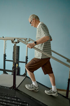 A senior man walks on a rehabilitation treadmill indoors