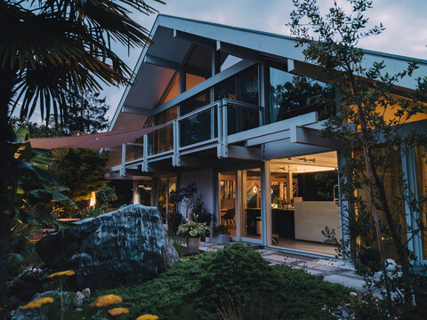 Modern timber frame villa illuminated at blue hour with garden