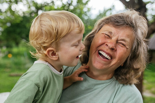 A grandmother and grandson share joyful laughter in the garden