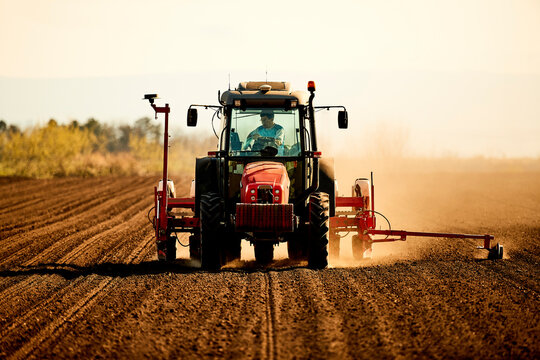Farmer in tractor seeding soybean crops working at farm field