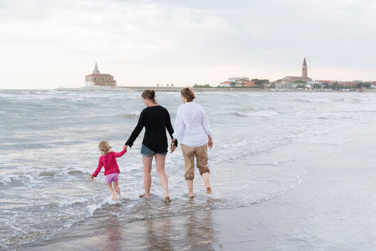 Italy, Caorle, two women walking with girl at the waterfront