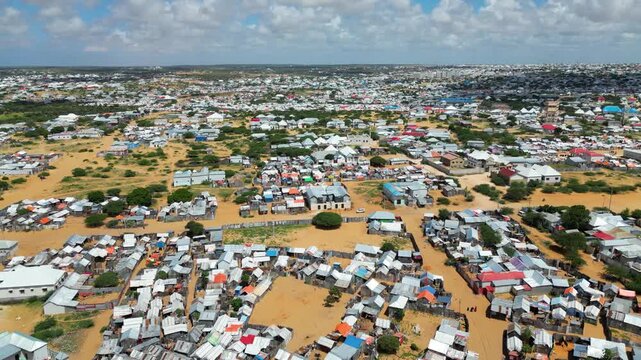 Panoramic birds eye view of an endangered rural settlement town or internally displaced persons camp layout in Somalia showcasing dry barren soil tracks and dense ma