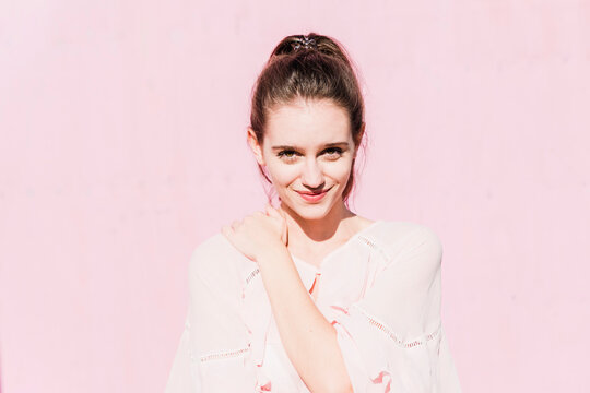 Portrait of smiling young woman in front of pink wall