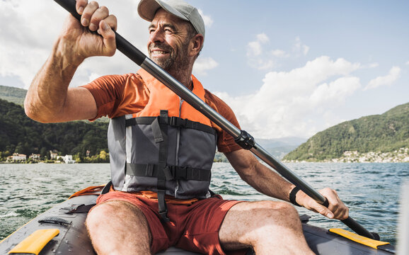 Smiling mature man rowing kayak boat on sunny day