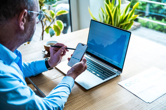 Man analyzes financial data on laptop and smartphone at the office