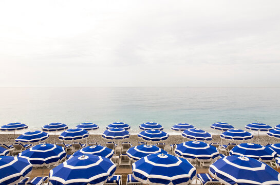 Empty deck chairs and beach umbrellas along coastal beach of French Riviera