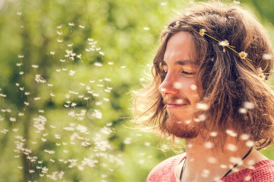 Young man enjoys flying dandelion seeds outdoors