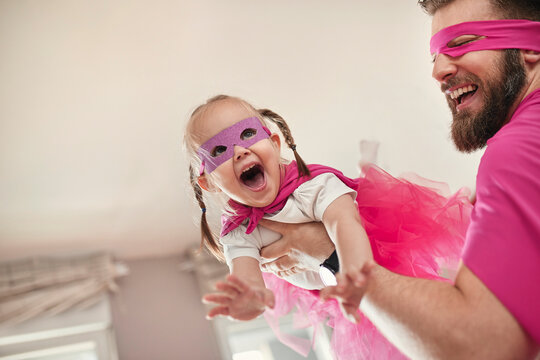 Father and daughter playing superhero and superwoman, pretending to fly