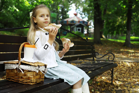 Girl Enjoying Picnic on Park Bench in Autumn