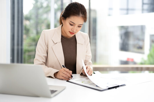 Business woman working in office reviewing checking documents. Accounting manager executive or lawyer using laptop reading paper file financial report.
