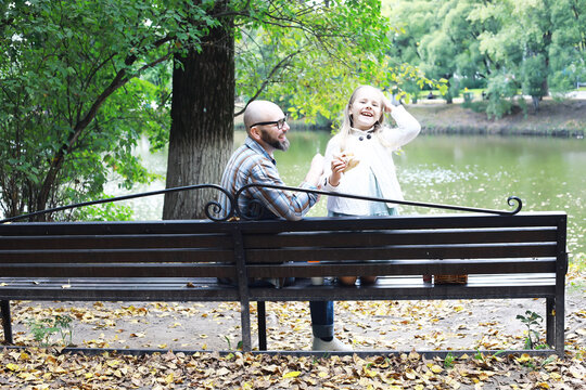 Father and Daughter Enjoying Ice Cream Together in a Park by the Lake