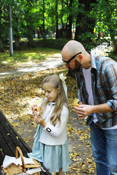 Father and Daughter Enjoying Picnic in Autumn Park with Fallen Leaves