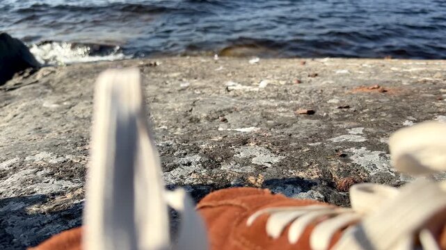 Water Lapping Against Rocky Lake Shore and red sneakers shoes